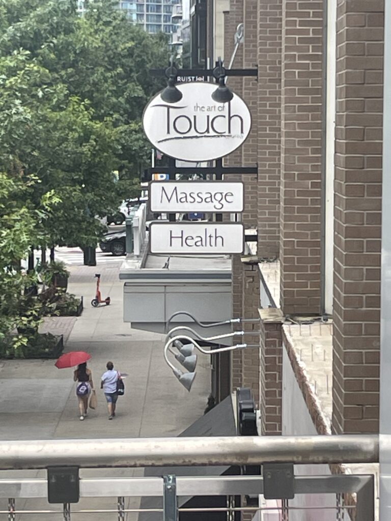 View from balcony showing The Art of Touch Massage sign and studio exterior on Peachtree St NE, Atlanta