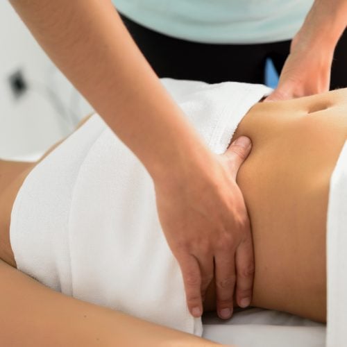 Hands massaging female abdomen.Therapist applying pressure on belly. Woman receiving massage at spa salon