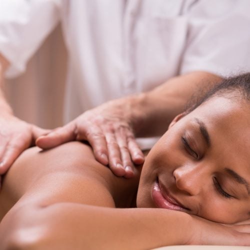 Relaxed young happy pretty woman and massage for painful shoulder